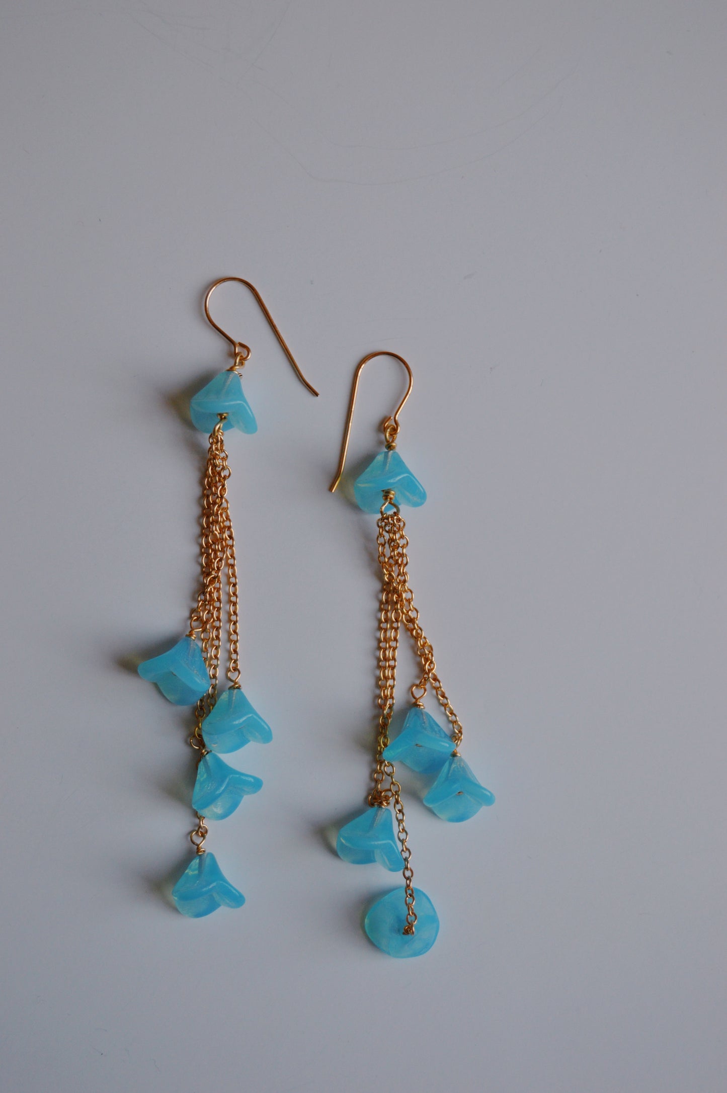 Bouquet Drops- Blueberry are dangle earrings with 14k gold-filled chains and several blue Czech Glass Tulips, expertly handcrafted and shown on a plain white background.