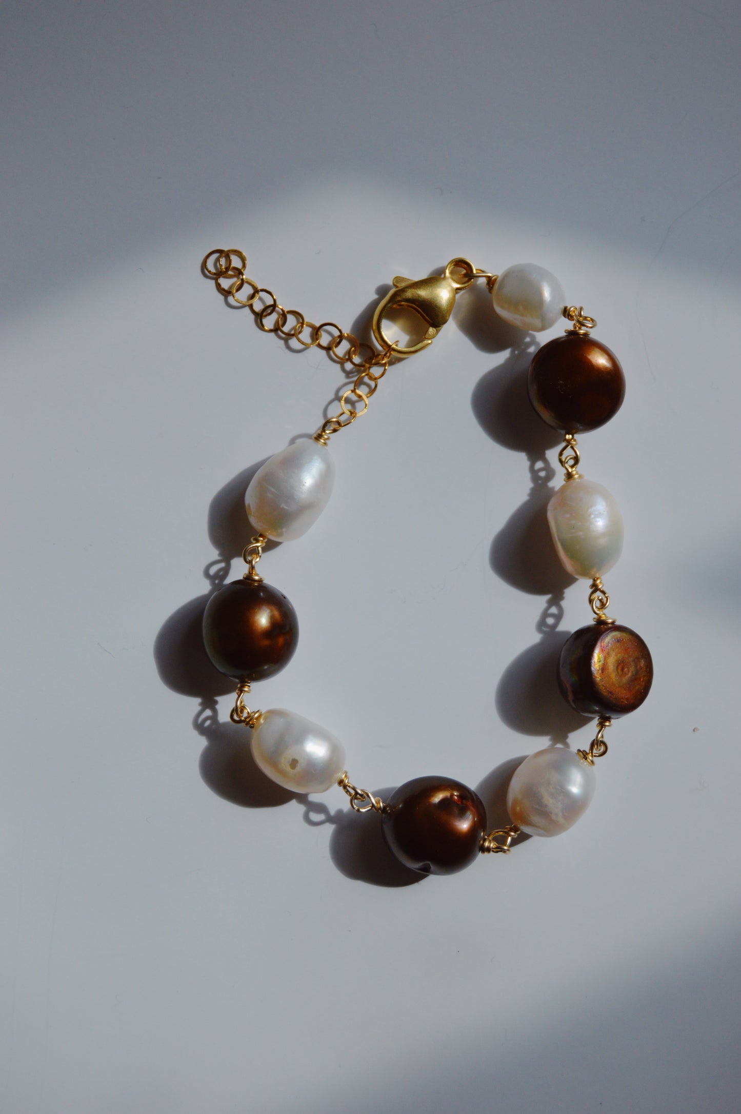 The Chocolate and White Pearl Bracelet features a 14k gold-filled chain with alternating round brown and irregular white cultured freshwater pearls, displayed on a light background—an elegant choice for your handmade bracelet collection.