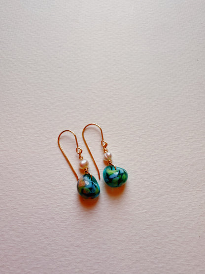 Bubble Minis: Dangle earrings with gold filled findings, small white glass beads, and blue heart-shaped floral pendants displayed on a textured white surface.