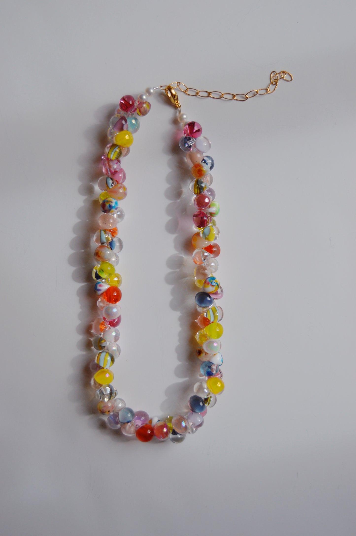 The Rainbow Bubble Glass Necklace in sugar features handmade lampwork glass beads and a gold adjustable chain clasp, displayed on a white background.
