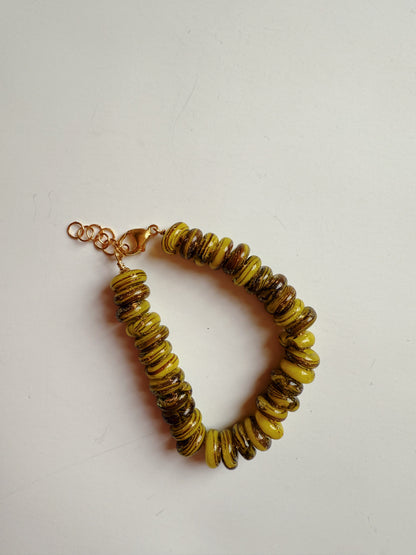 The Donut Bracelet features chunky, round yellow and brown handblown glass beads alternately arranged on a 14k gold filled chain with a clasp, shown against a plain white background.