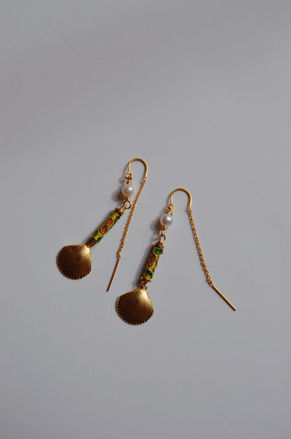 The Cloisonne Shell Threaders are gold drop earrings featuring scallop shell-shaped pendants, cultured freshwater pearls, and green and red detailing—handcrafted artisan jewelry that shines on a plain white background.