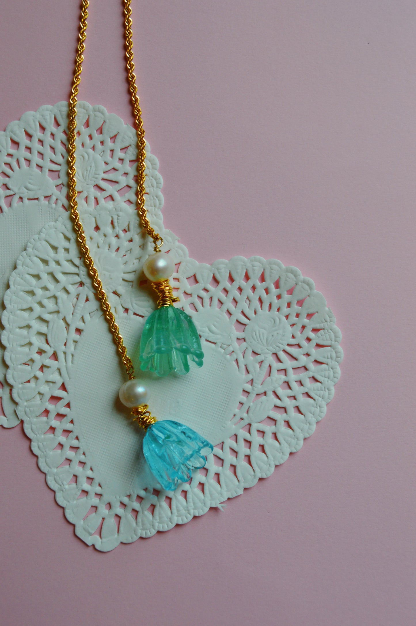 The Tulip Wrap Necklace-Bluebells features a heart-shaped pendant accented with two blue and green beads and delicate cultured freshwater pearls.