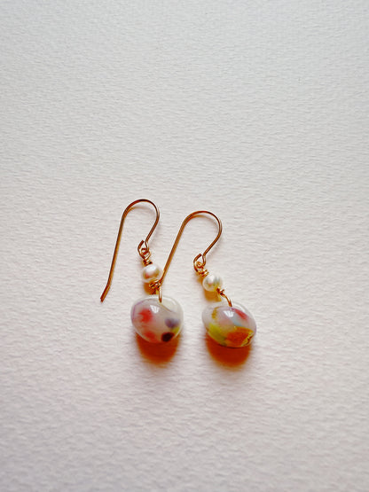 Bubble Minis earrings feature gold-filled findings and a small freshwater pearl above a round multicolored glass bead with red, green, and yellow accents, displayed on a textured white background.