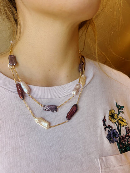 A woman wearing a white shirt and the Saturday Layer—a double-layered 14K gold filled chain with mixed rectangular pearls and irregular purple and white beads—shown from the shoulders up.