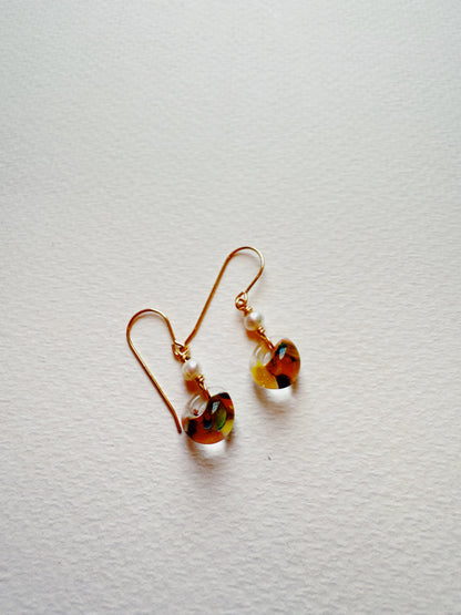 The Bubble Minis are gold hook earrings featuring round, multicolored glass beads with small white accents, displayed on a textured white surface.