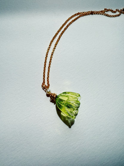 The Tulip Necklace is a 14k gold filled chain with a green handblown glass tulip pendant and a small cultured freshwater pearl, shown on a white background.