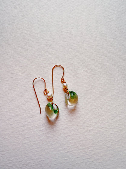 Bubble Minis earrings feature gold-filled findings with a small round glass bead accented in green and a freshwater pearl above, shown on a light textured background.