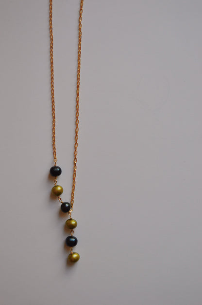 The Six Pearl Lariat—Blue and Green Mix is a handcrafted necklace featuring six alternating blue and green pearls in a vertical line on a 14k gold-filled chain, showcased against a plain light background.