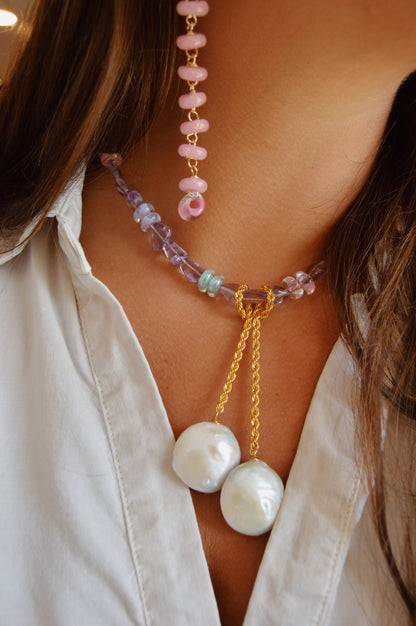 A close-up of a person wearing the Amethyst Dreams Layer—a colorful strand with handblown glass beads, two large cultured freshwater pearls, and a 14k gold filled chain—alongside a white collared shirt and pink beaded necklace.