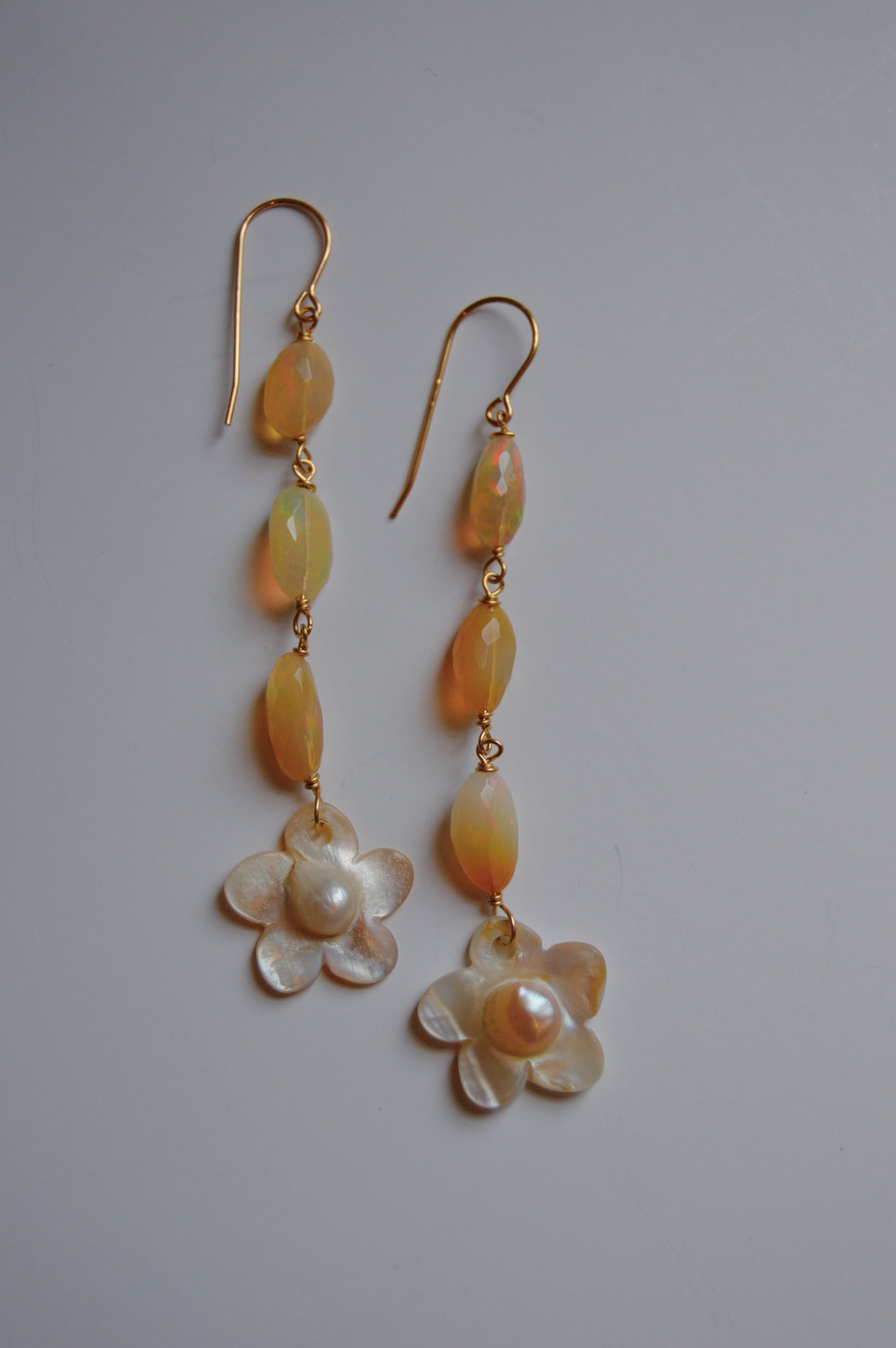 Opal & Pearl Flower Drops feature 14k gold-filled hooks, three oval yellow beads, and a Mother of Pearl flower charm, displayed on a plain light background.