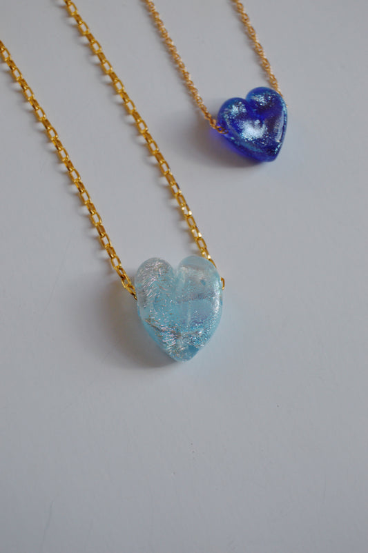 Two Glass Heart Necklaces- Blues, each featuring a handmade lampwork glass heart pendant in light blue or dark blue on a gold-filled chain, are displayed on a white background.