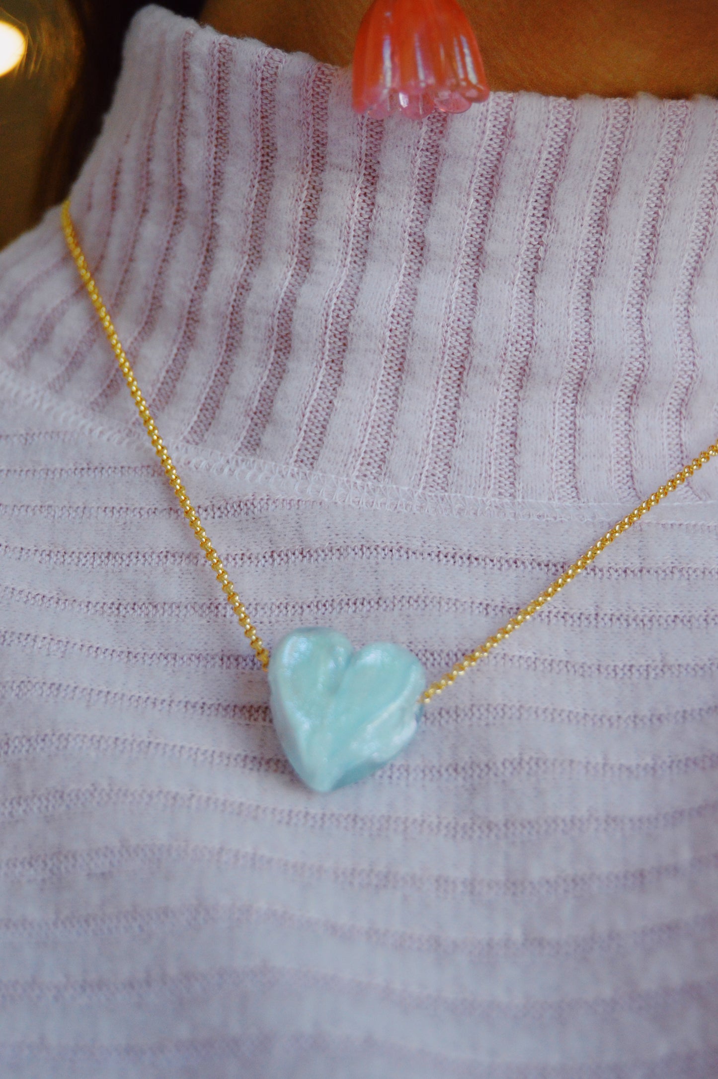 A person in a ribbed light purple turtleneck wears a gold-filled chain with a handmade Glass Heart Necklaces- Blues pendant around their neck.