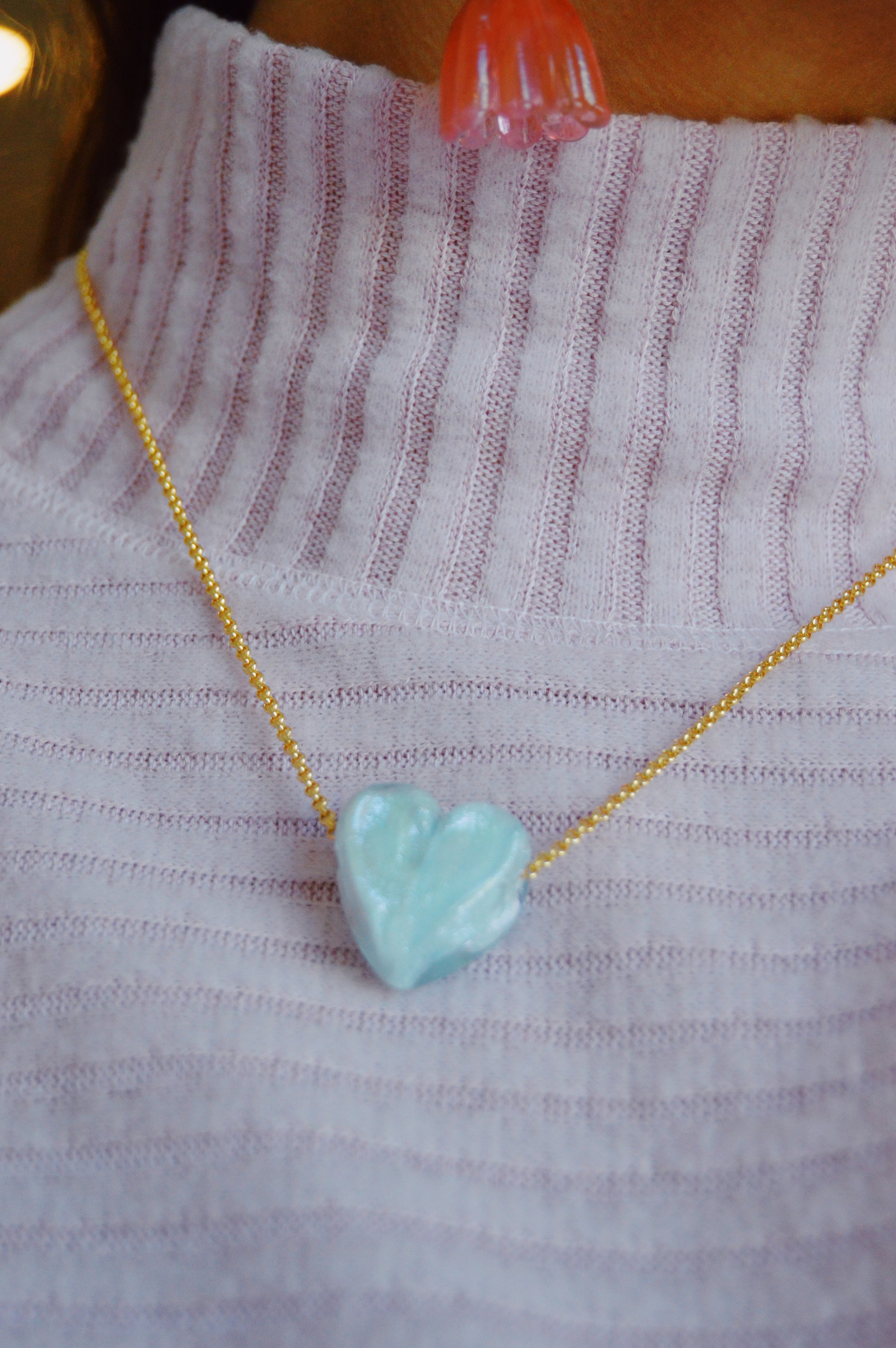 A person in a ribbed light purple turtleneck wears a gold-filled chain with a handmade Glass Heart Necklaces- Blues pendant around their neck.