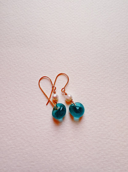 Bubble Minis: Gold hook earrings with gold-filled findings, white freshwater pearls, and translucent blue circular glass beads, displayed on a light textured surface.