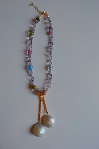 The Amethyst Dreams Layer is a beaded necklace with multicolored handblown glass beads and two large round white pendants on a 14k gold filled chain, displayed on a plain light surface.