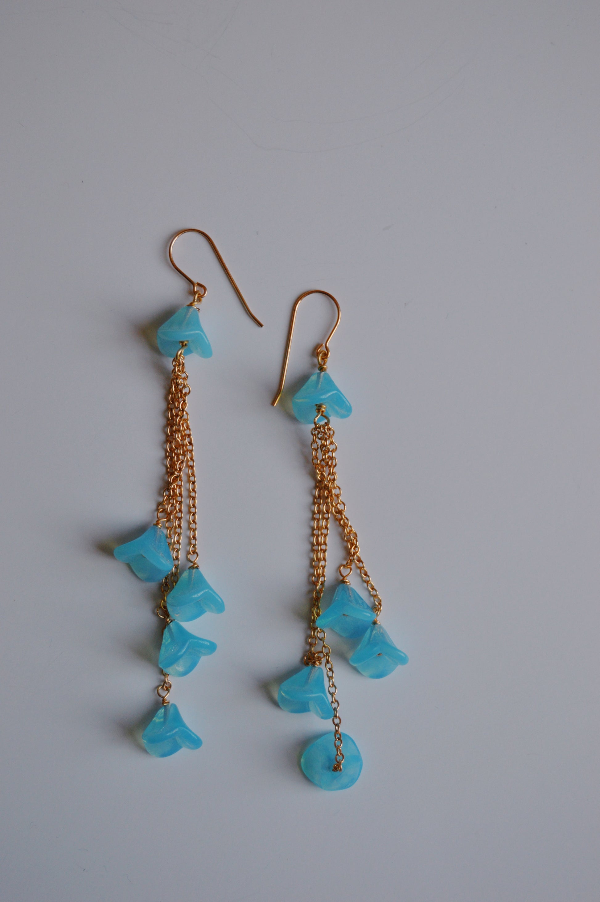 Bouquet Drops- Blueberry are dangle earrings with 14k gold-filled chains and several blue Czech Glass Tulips, expertly handcrafted and shown on a plain white background.