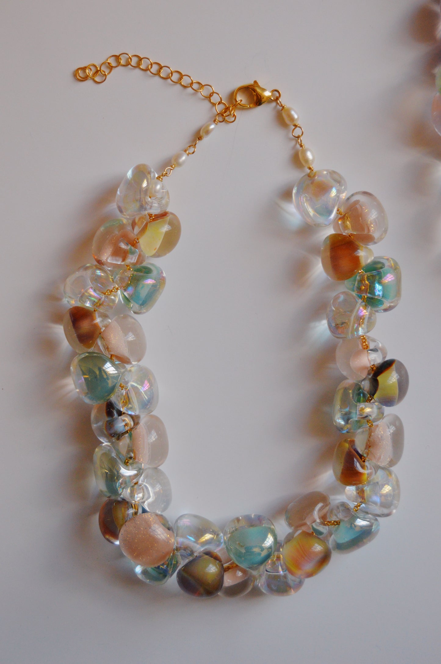 The Grand Bubble Necklace- Muted Mix features large, translucent, multicolored handmade lampwork glass beads on a 14k gold-filled chain and clasp, arranged in a loose oval on a white background.