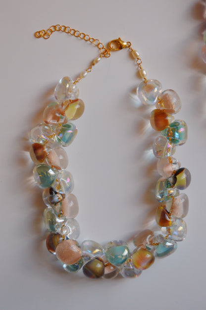 The Grand Bubble Necklace- Muted Mix features large, translucent, multicolored handmade lampwork glass beads on a 14k gold-filled chain and clasp, arranged in a loose oval on a white background.