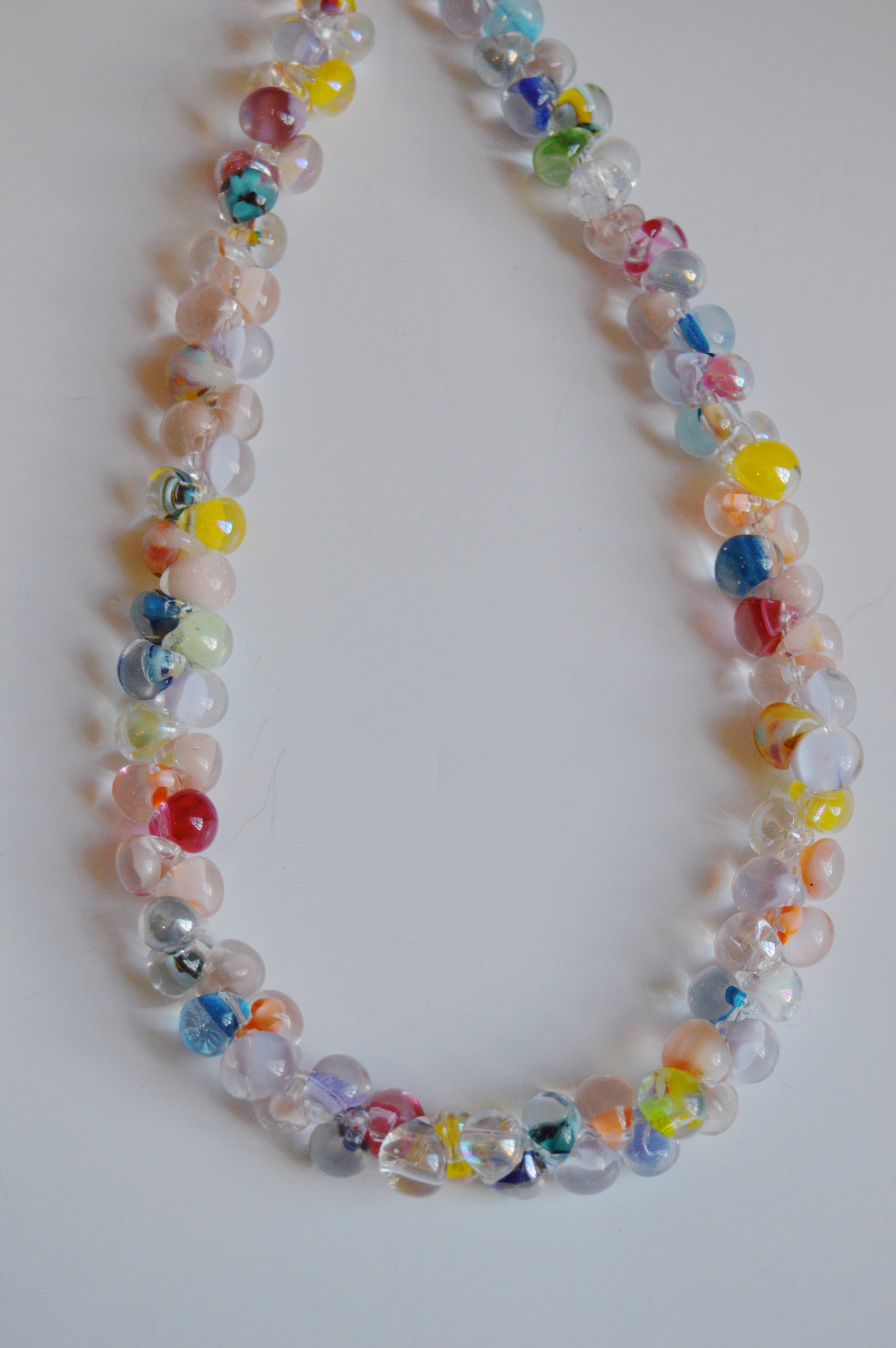 The Rainbow Bubble Glass Necklace features handmade, round translucent glass beads in a candy color mix, strung together in a loop and displayed on a plain white background.