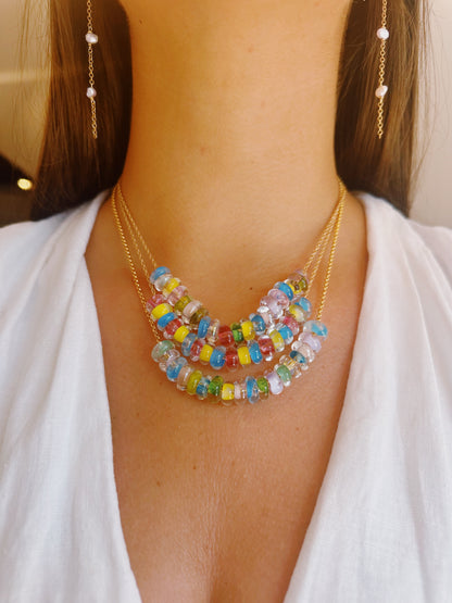 A woman in a white top layers the Lots of Donuts Layer, a 14k gold filled chain necklace with handblown glass beads, paired with dangling gold filled earrings featuring small pearls.