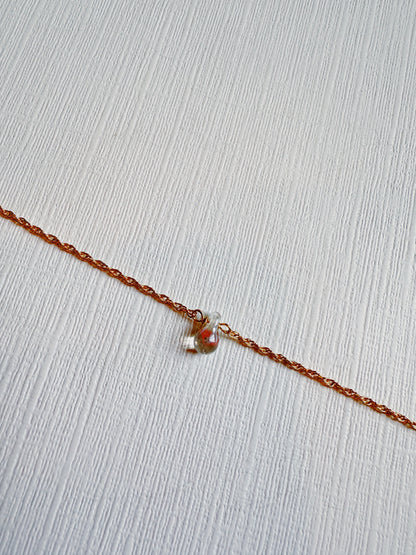 The Dewdrop Bracelet is an adjustable piece featuring a 14k gold filled chain and anchor-shaped charm, elegantly displayed on a textured white surface.