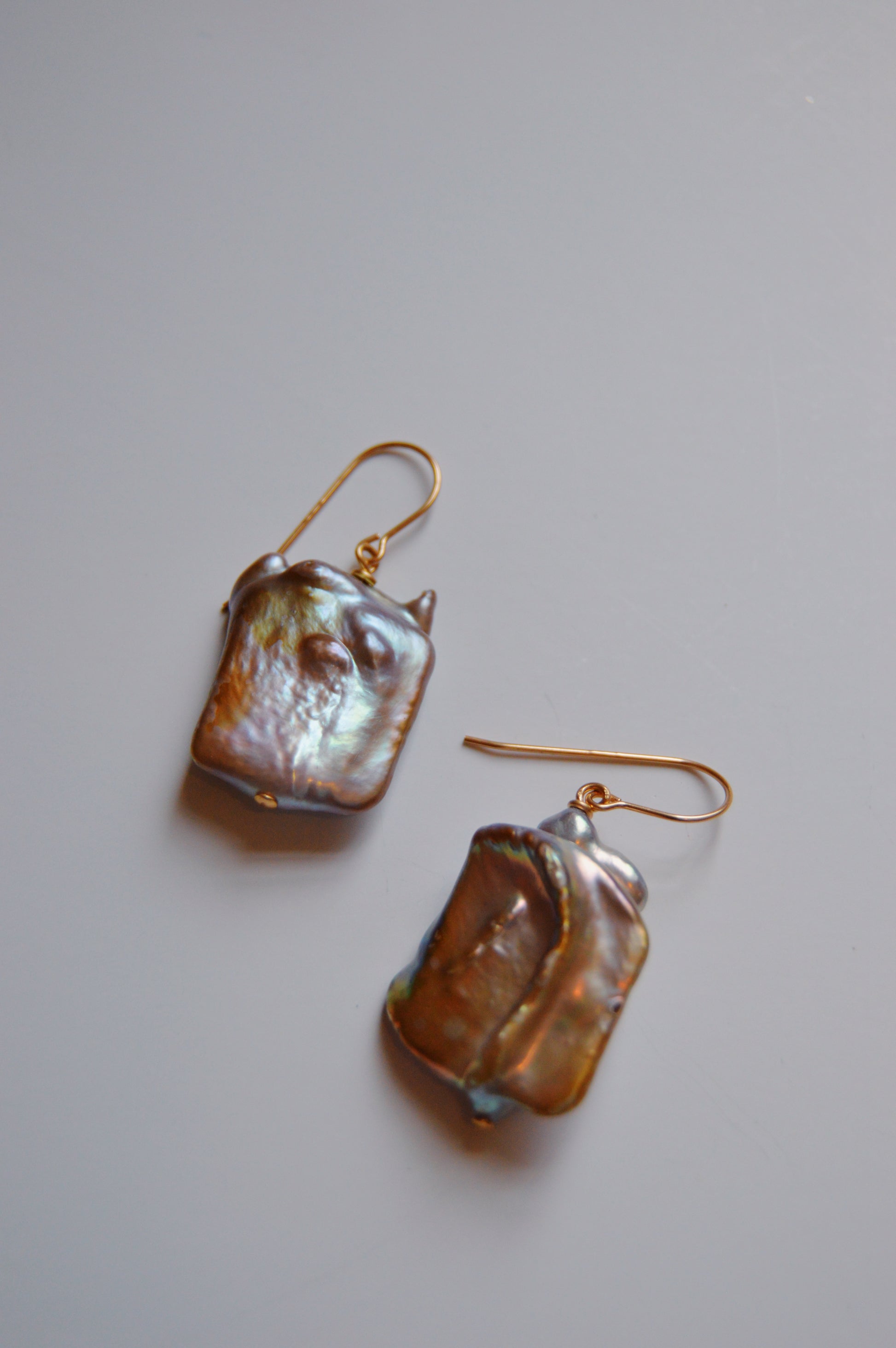 Pearl Drops are handcrafted 14k gold-filled hook earrings with large, irregular cultured freshwater pearls, shown on a plain light surface.