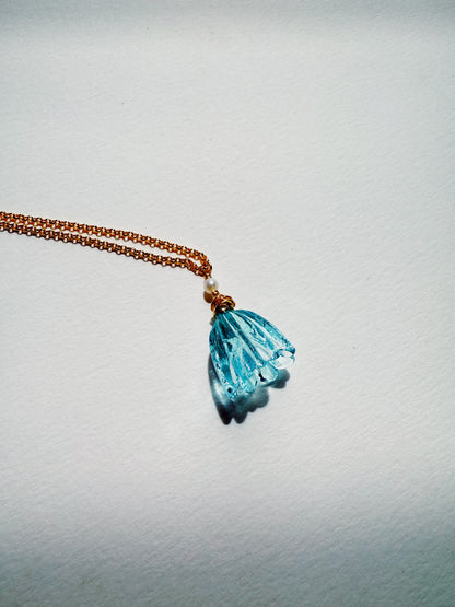 The Tulip Necklace features a handblown blue glass tulip pendant and a small white bead on a 14k gold filled chain, displayed against a plain white background.