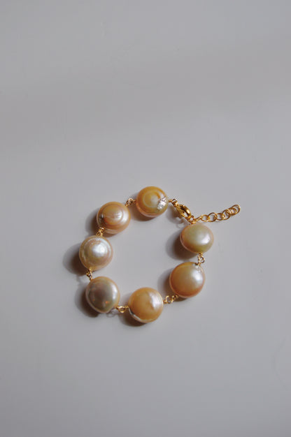 The Circle Pearl Bracelet features seven large round cultured freshwater pearls set in 14k gold-filled links, with an adjustable chain and clasp. Displayed on a plain light background, it’s ideal for handmade bracelet enthusiasts.