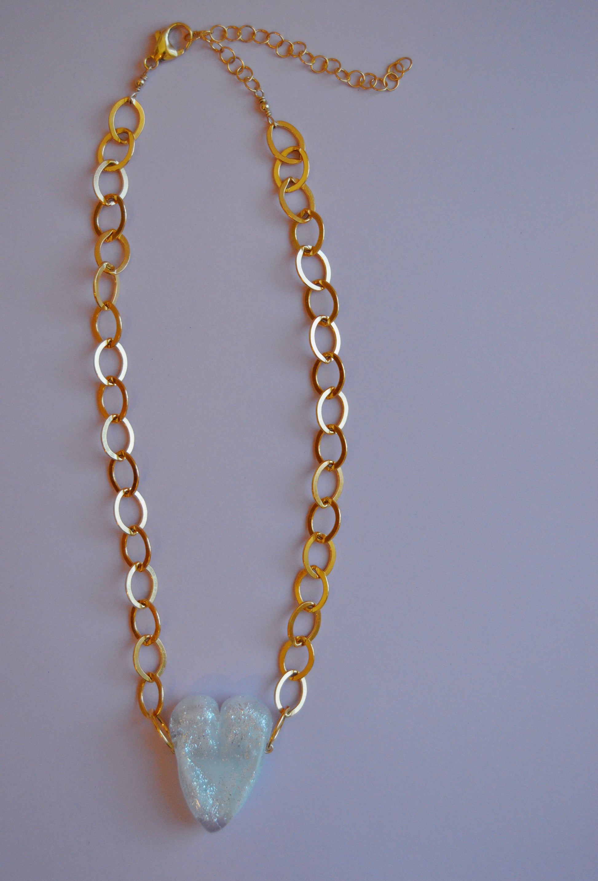 The White Glass Heart on Chunky Gold Filled Chain features a handmade white glass heart pendant on a gold-filled chain with circular links—an elegant piece of artisan jewelry displayed against a plain light background.