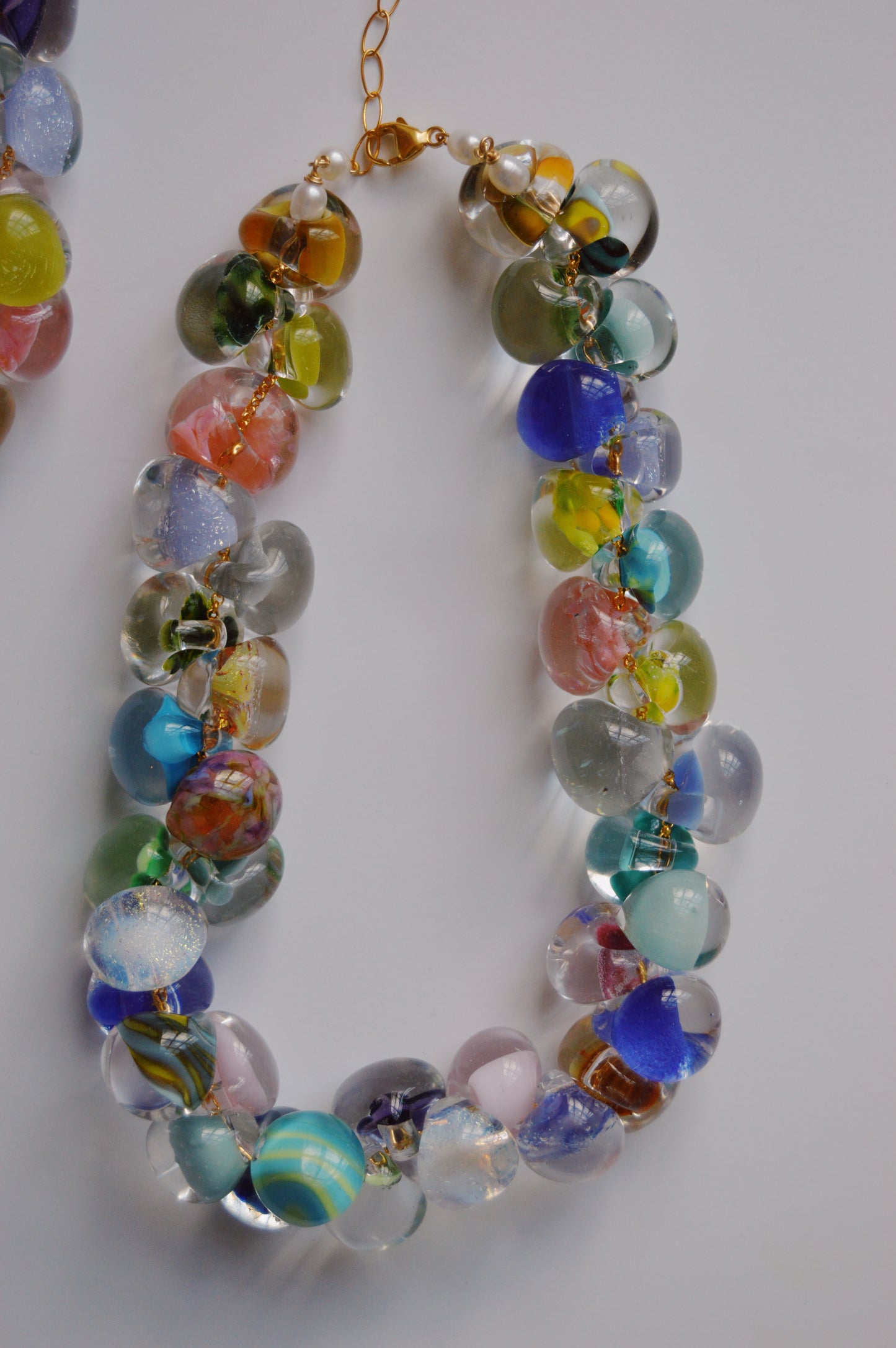 The Grand Bubble Glass Necklace- Poolside Mix features large, hand-crafted multicolored lampwork beads with transparent and opaque patterns, strung on a gold chain with 14k gold-filled findings—an eye-catching piece against a white background.