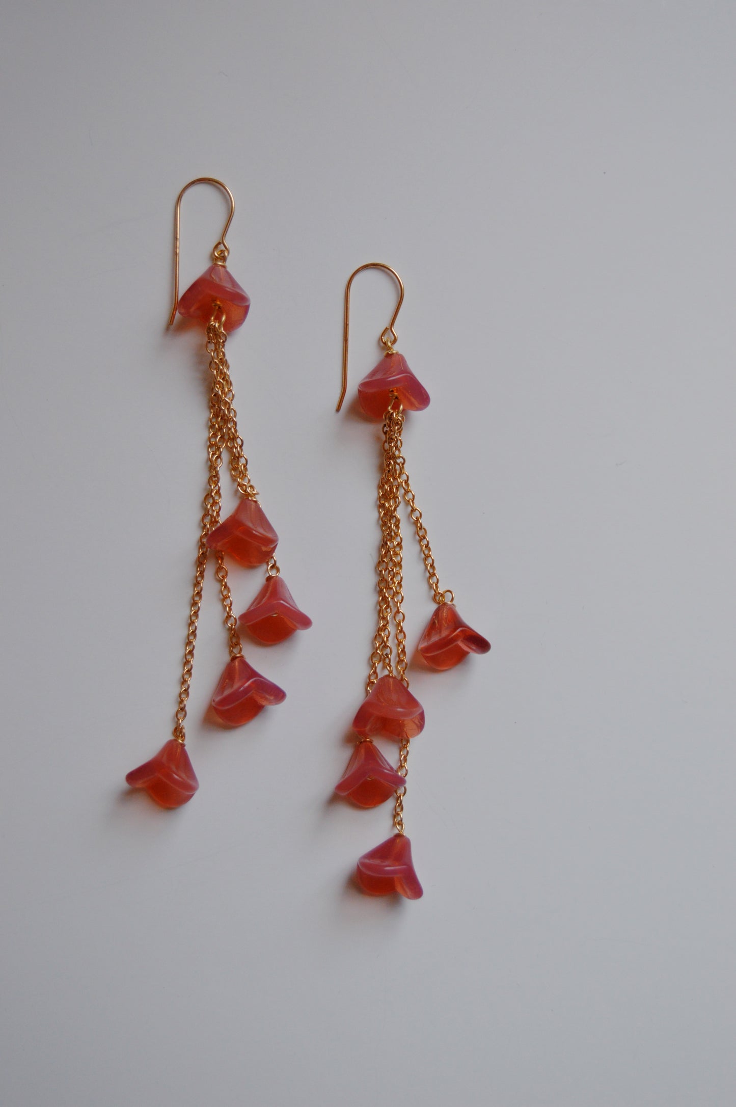 A pair of Bouquet Drops- Raspberry earrings featuring 14k gold-filled chains and pink, petal-shaped Czech glass tulips at staggered lengths, shown on a plain white background.