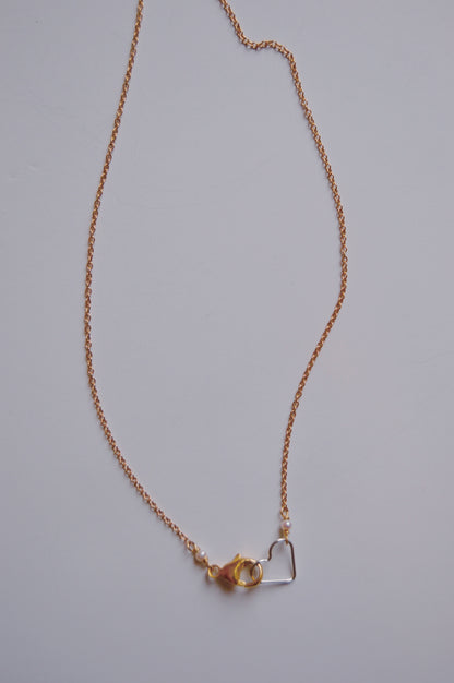 The Clasp in Front Layer necklace features a delicate 16" oxidized sterling silver chain with a lobster clasp and a small 14K gold-filled heart pendant, shown against a plain white background.