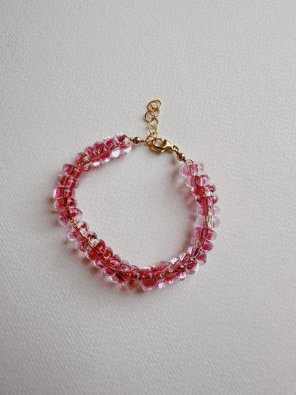 The Donut Bracelet features pink and clear handblown glass beads on a 14k gold filled chain with an adjustable clasp, shown against a light textured background.