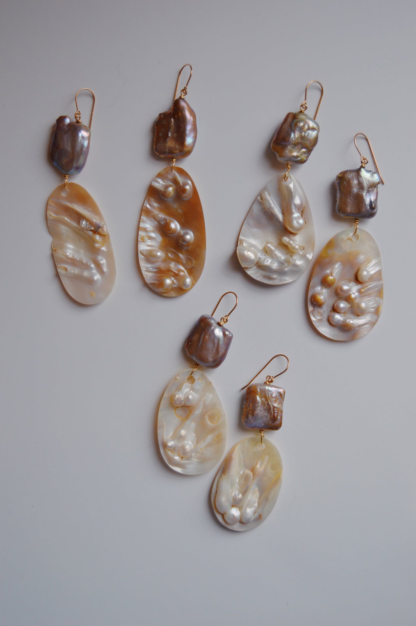 The Angel Shell Drops set includes three pairs of dangle earrings with shiny mother-of-pearl and baroque cultured freshwater pearls, accented in 14k gold-filled details, all shown against a plain light background.