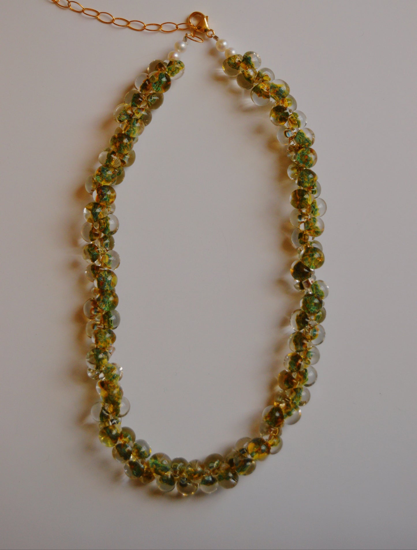 The Bubble Glass Necklace- Clover is a handmade necklace with green and yellow glass beads, clear round beads, and cultured freshwater pearls, finished with 14k gold-filled findings and a gold chain extender clasp.