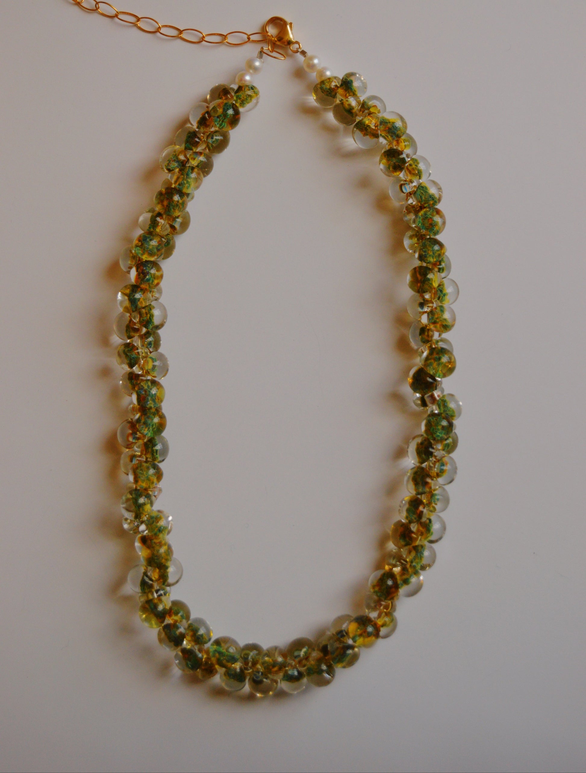 The Bubble Glass Necklace- Clover is a handmade necklace with green and yellow glass beads, clear round beads, and cultured freshwater pearls, finished with 14k gold-filled findings and a gold chain extender clasp.