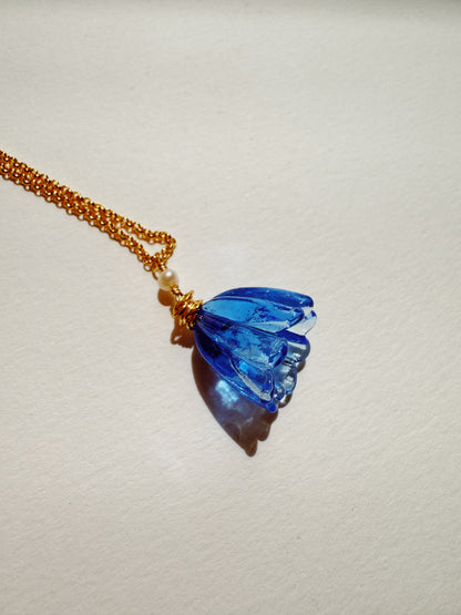 The Tulip Necklace features a handblown blue glass tulip flower pendant on a 14k gold filled chain, displayed on a light surface with a soft shadow.