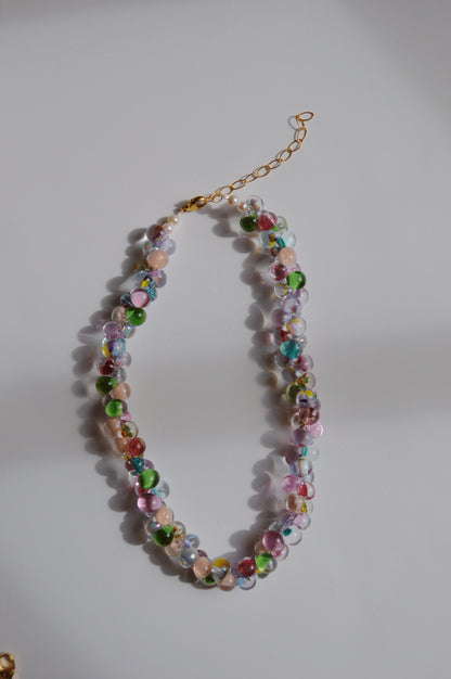 The Bubble Glass Necklace- Bloom Mix features colorful, round handmade glass beads in shades of green, pink, blue, and clear with a gold adjustable chain clasp.