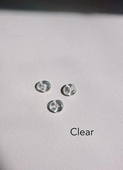 Three small, clear, round Glass Donut Threaders rest on a textured white surface, with the product name in black text at the bottom right.