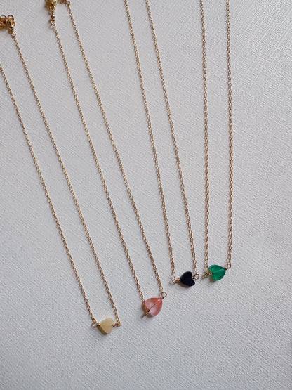 Five Boyfriend Necklaces are displayed side by side, each with a small heart-shaped pendant in cream, pink, blue, black, and green—an elegant showcase of gold filled jewelry on a light textured surface.