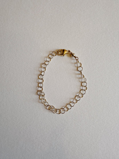 The Dainty Silver Bracelet features small circular links and a lobster clasp, elegantly displayed on a light, neutral background.