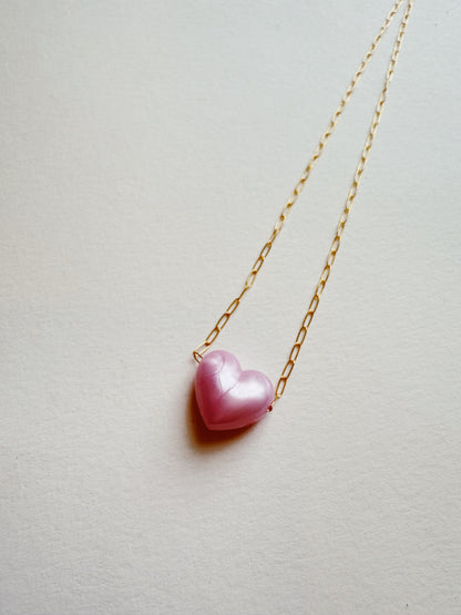 The Acrylic Heart Necklace, featuring a pink acrylic heart pendant on a gold filled chain, is shown against a plain light background.