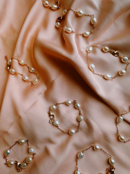 The Pearl Bracelet features hand-wired cultured freshwater pearls on 14k gold filled links, arranged on peach fabric for a soft, elegant look and a sophisticated touch.
