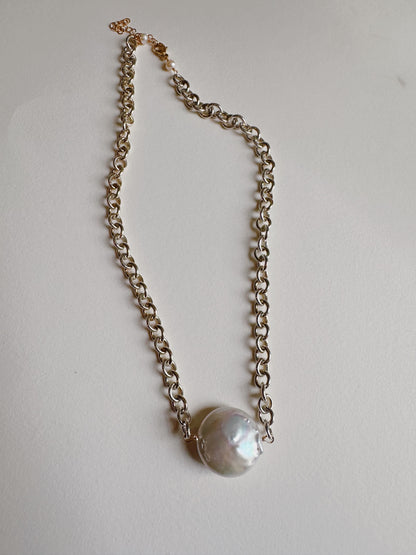 The Sterling Chunky Pearl Layer features a large, round cultured freshwater pearl pendant on a gold chain with 14k gold filled findings, elegantly displayed on a light surface.