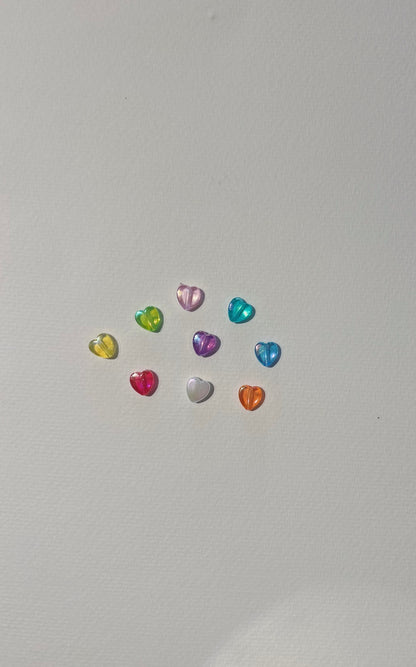 Ten colorful, shiny Acrylic Heart Beads—yellow, pink, blue, green, red, orange, purple, and clear—are arranged in a loose semicircle on a white background to showcase the Friendship Bracelet.