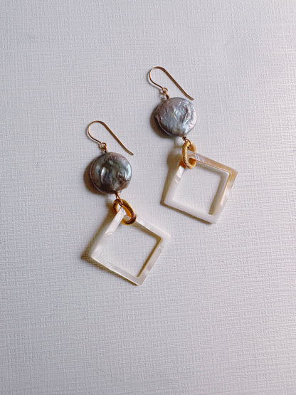 Diamond Shell and Pearl Drops: Round iridescent gray cultured freshwater pearl studs with dangling open square translucent shapes, linked by gold filled findings, displayed on a textured white background.