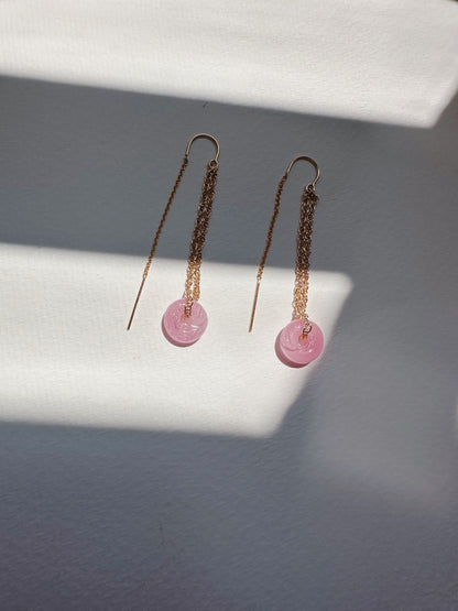 The Glass Donut Threaders—14k gold filled earrings with pink round pendants and handblown glass beads—are displayed on a white textured surface with diagonal shadows in the background.