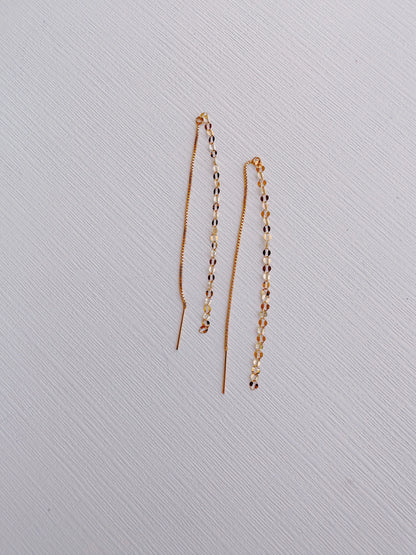 Glitzy Threaders: Delicate 14k gold filled threader earrings with a beaded design of alternating white and dark beads along a chain, displayed on a textured white surface.
