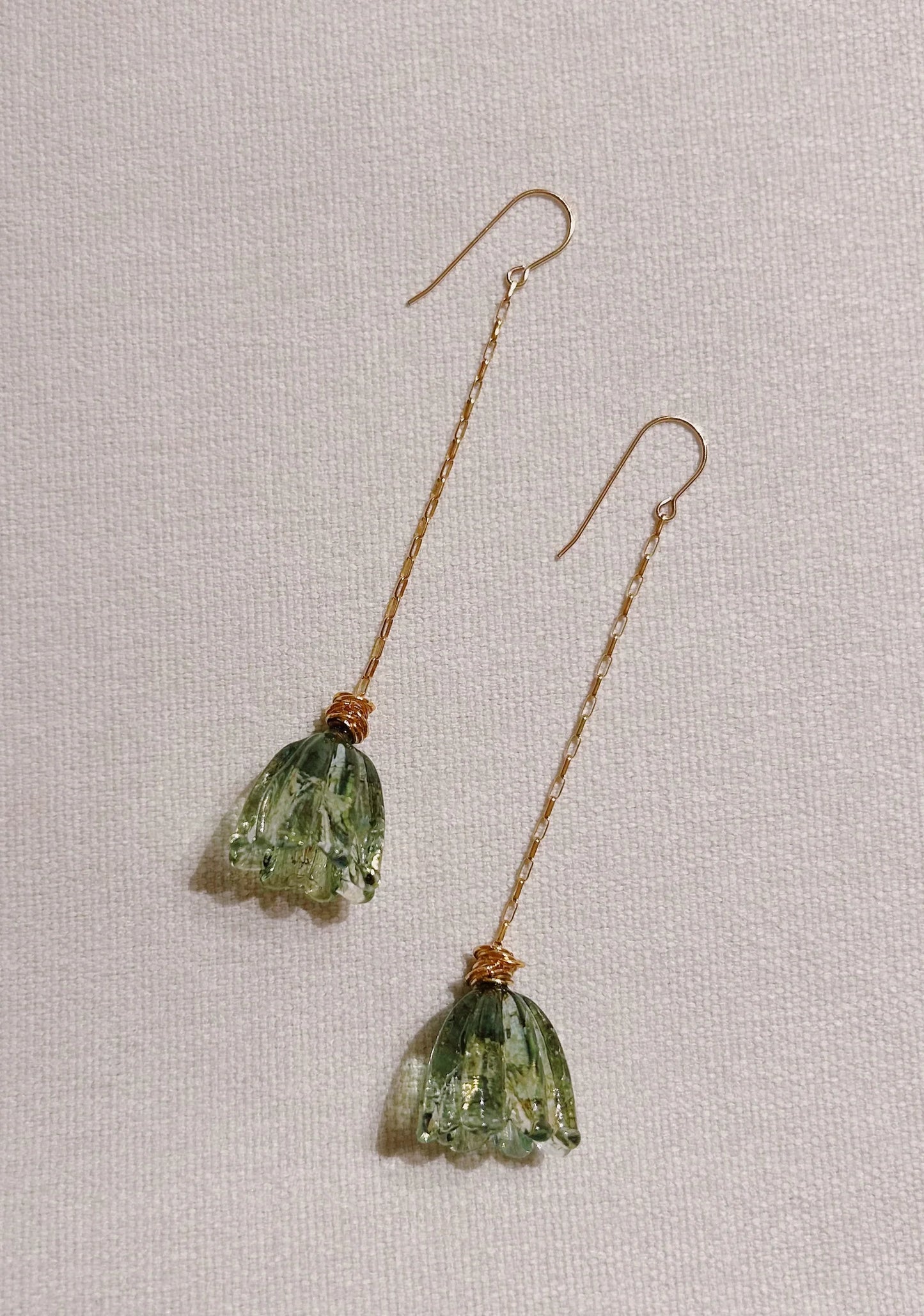Glass Tulip Earrings in jade feature long gold hooks and delicate, translucent handmade tulip details, expertly crafted by skilled glass artists and shown on a light textured background.